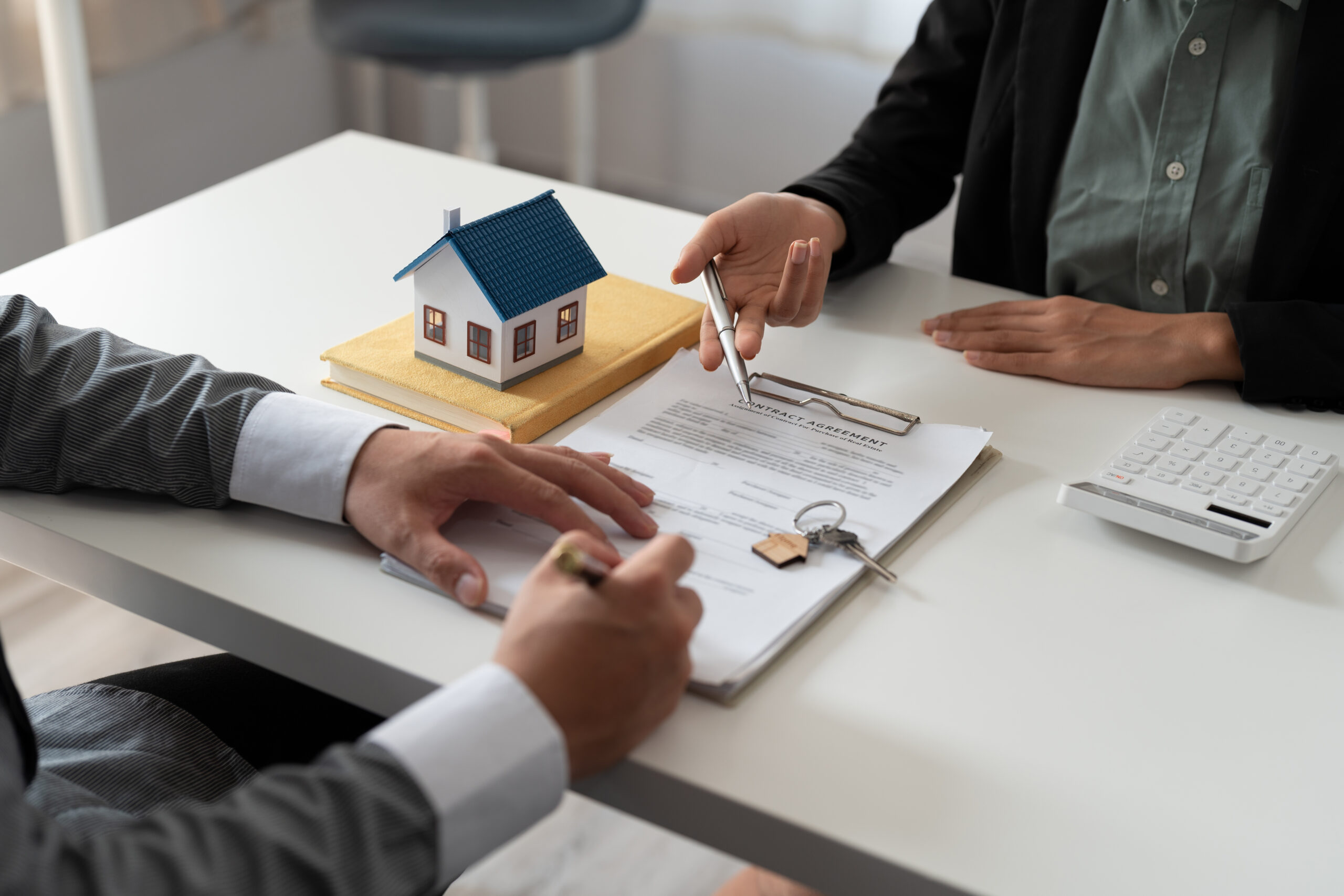 Real estate agent holding house key to his client after signing